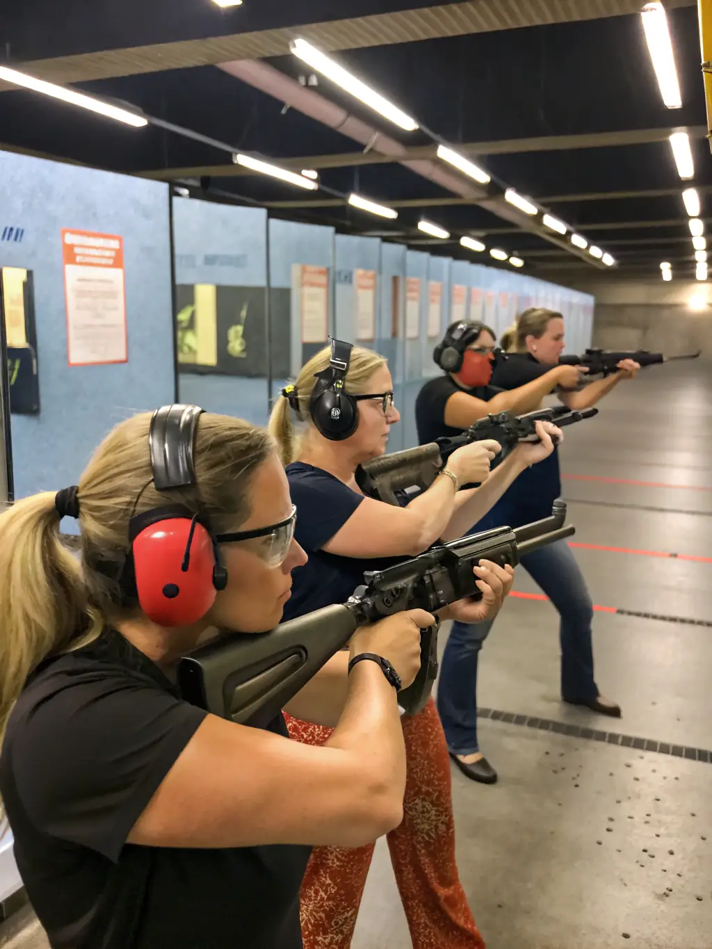 A group of people practicing recreational shooting at the range, wearing safety gear and aiming at targets.